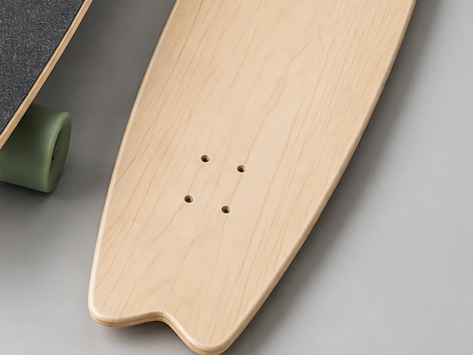Close view of a maple surfskate deck with a shaped tail and layered edge